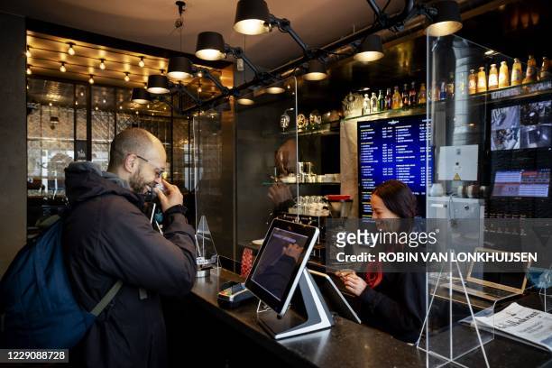 Customer collects products at a coffee shop in Amsterdam on October 15, 2020. - Like catering establishments, coffee shops must remain closed...