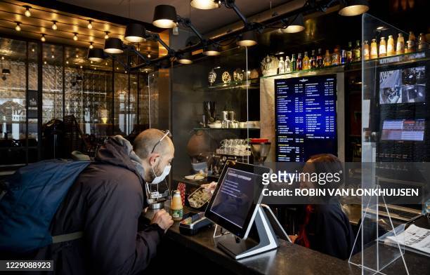 Customer collects products at a coffee shop in Amsterdam on October 15, 2020. - Like catering establishments, coffee shops must remain closed...
