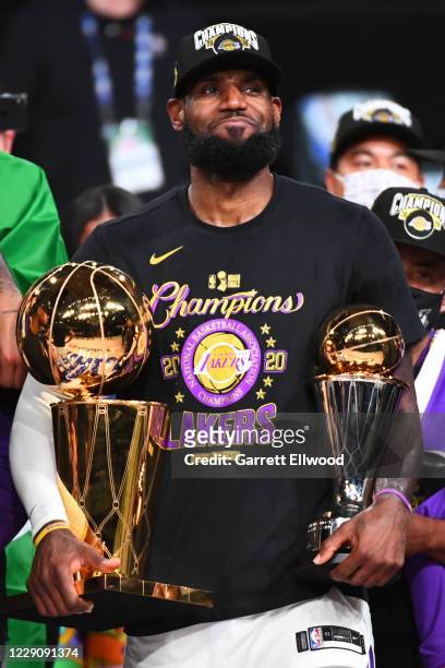 LeBron James of the Los Angeles Lakers celebrates with the Larry O'Brien Finals Trophy and Bill Russell Finals MVP Trophy after Game Six of the NBA...