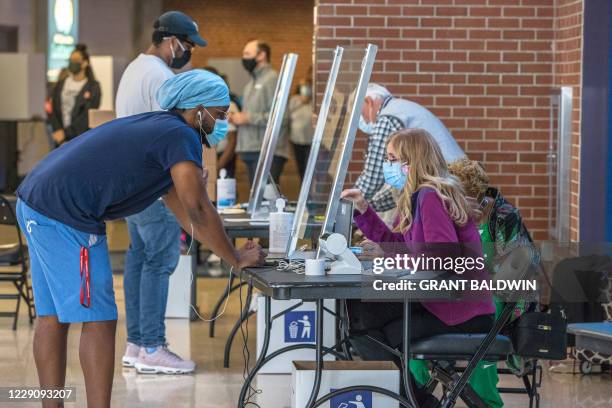 Poll worker assists a voter at the Spectrum Center, during the first day of early voting in Charlotte, North Carolina, on October 15, 2020.