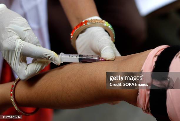 Health worker wearing protective gloves draws blood from a man for a Covid-19 antibody test at a government dispensary. India's coronavirus confirmed...