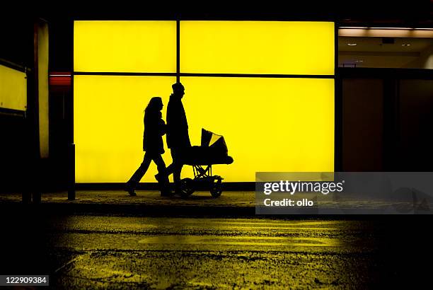 couple with baby buggy in front of a illuminated facade - carriage stock pictures, royalty-free photos & images