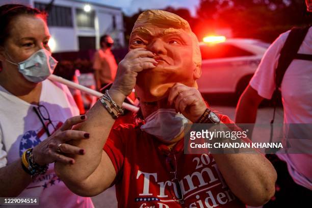 Supporter of US President Donald Trump wears a mask prior to his arrival for an NBC News town hall event at the Perez Art Museum in Miami on October...