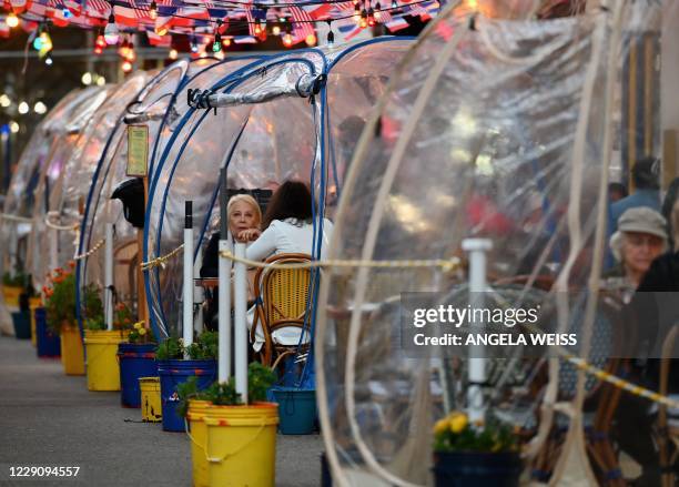 People dine in plastic tents for social distancing at a restaurant in Manhattan on October 15, 2020 in New York City, amid the coronavirus pandemic.