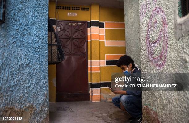 Jonathan Figueroa uses his cellphone, connected to a neighbour's wifi signal, outside his home at the Bello Campo neighborhood in Chacao, Caracas, on...