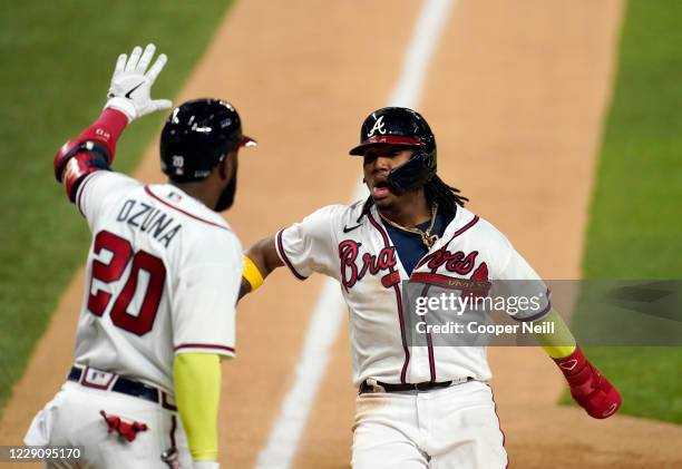 Marcell Ozuna congratulates Ronald Acuna Jr. #13 of the Atlanta Braves as he scores in the bottom of the sixth inning of Game 4 of the NLCS between...