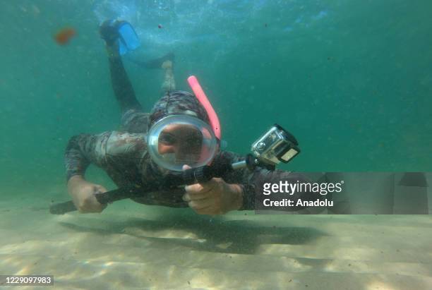 Year-old Palestinian photographer, Muhammed Asad, wearing a diving suit, records during an underwater shooting of a documentary footage on...