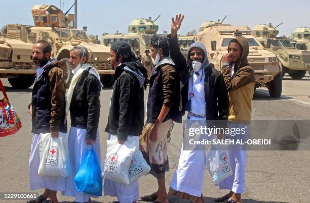 International Red Cross workers and Yemeni officials coordinate as prisoners walk towards a plane used to carry them to the rebel-held capital Sanaa,...