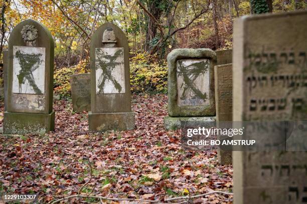 This photo taken on November 10, 2019 shows tombstones painted with green graffiti and some overturned at the Oestre Kirkegaard Jewish cemetery in...