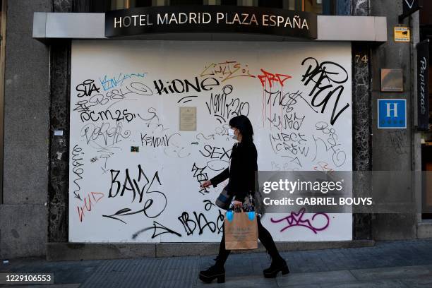 Woman walks past a closed hotel on Gran Via, the main avenue of central Madrid, on October 16, 2020. - The coronavirus pandemic has pulverised...