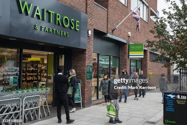 Shoppers wearing face coverings to help prevent the spread of the coronavirus queue outside a Waitrose store on 16 October 2020 in Weybridge, United...