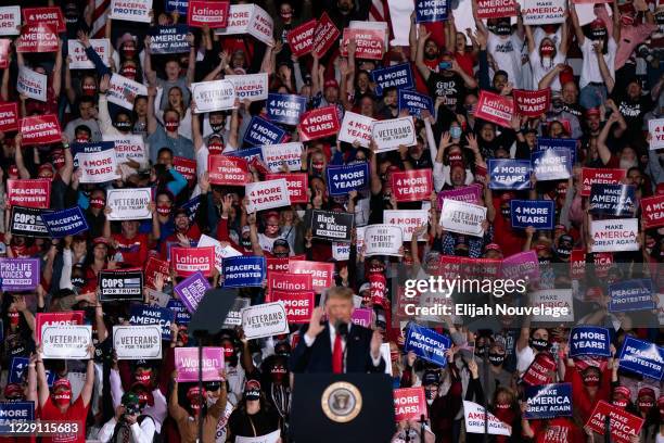 Attendees cheer and hold up signs as President Donald Trump speaks at a campaign rally on October 16, 2020 in Macon, Georgia. President Trump...