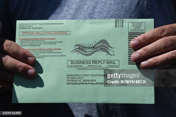 Voter displays their mail-in ballot envelope as they arrive to cast their ballot in the US presidential election at an early voting location in...