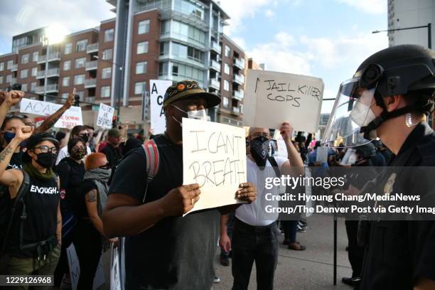 Rasllula Housch, center, holds a sign as protestors face off with Denver Police officers near 20th St. And Chestnut Pl. In Denver on Thursday...