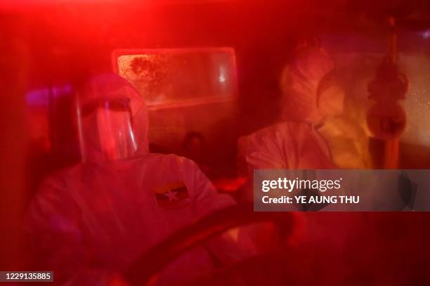 This photo taken on October 17, 2020 shows volunteers wearing personal protective equipment sitting inside an ambulance as local residents suspected...