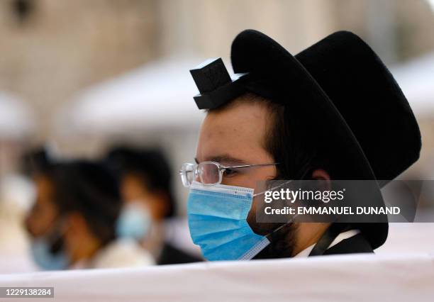 An Ultra-Orthodox Jewish man wearing a facemask and a tefillin prays at the Western Wall in the Old City of Jerusalem on October 18 amid the novel...