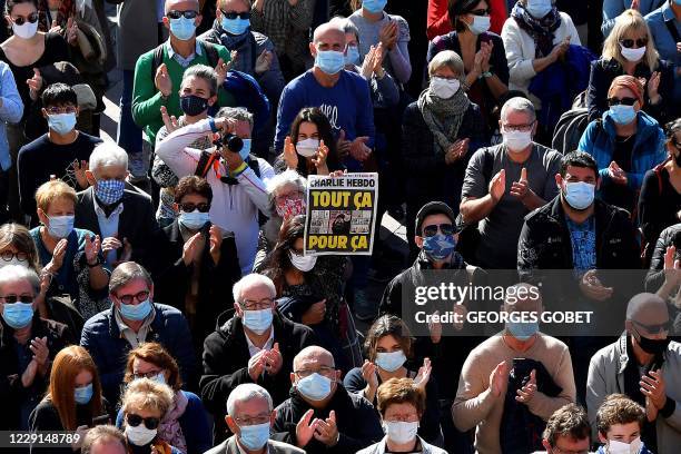 People gather as as person holds a cover of French satirical weekly Charlie Hebdo reading "All of this, just for that'', Place du Capitole in...