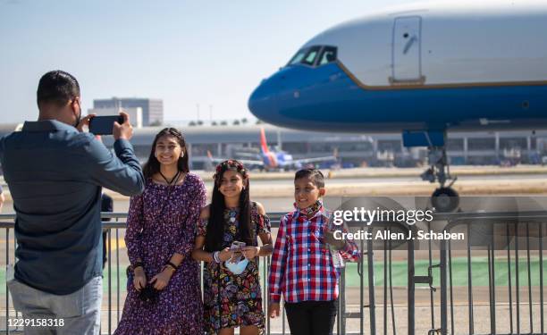 Trump supporters Hector Franco, left, of Santa Ana, takes a photo of his kids, Mia Melinda and Maximo, after seeing President Donald Trump greet...