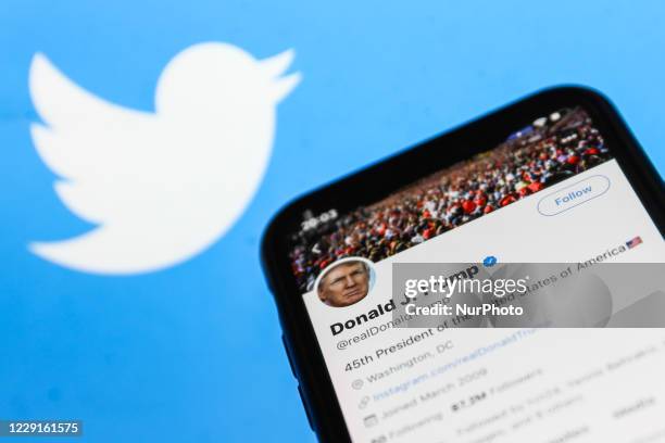 Twitter feed of the President of the USA Donald Trump is seen displayed on a phone screen with Twitter logo in the background in this illustration...