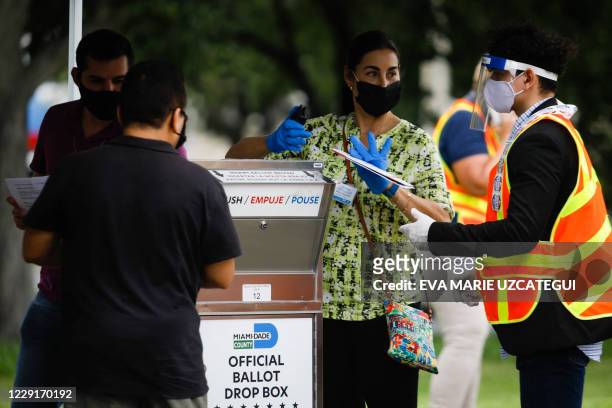 Poll workers are seen at a ballot drop box at Miami-Dade County Election Department in Miami, Florida on October 19, 2020. Early voting kicked off...