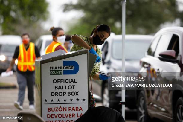 Poll worker drops off a vote-by-mail ballot at a ballot drop box at Miami-Dade County Election Department in Miami, Florida on October 19, 2020....