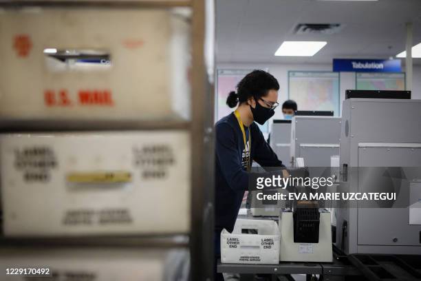An electoral worker scans vote-by-mail ballots at the Miami-Dade County Election Department in Miami, Florida on October 19, 2020. Early voting...