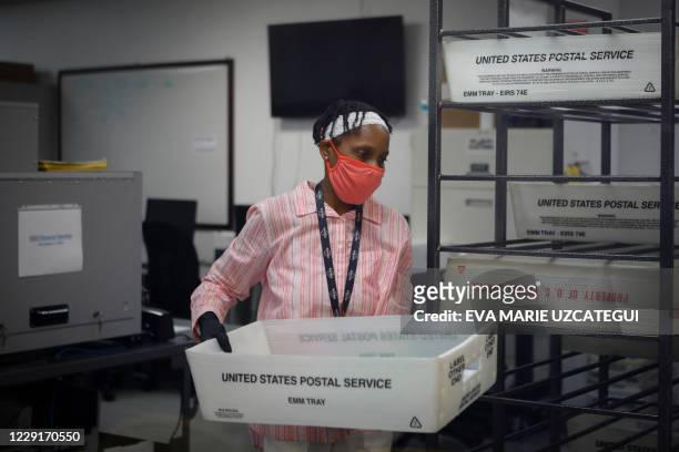An electoral worker carries a US Postal Service bin with Vote-By-Mail ballots at the Miami-Dade County Election Department in Miami, Florida on...