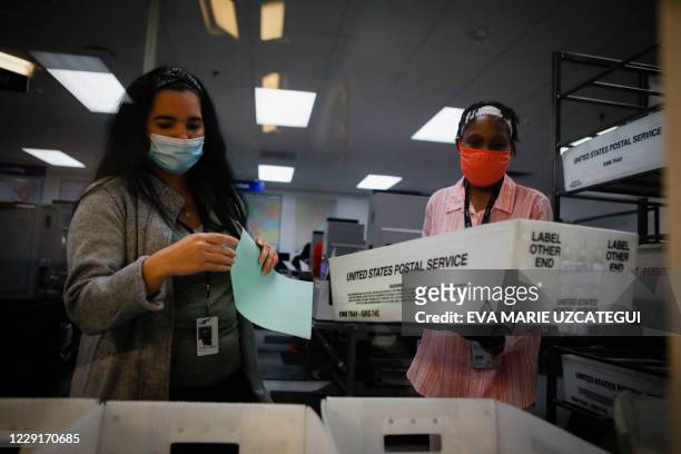 Electoral worker are seen during the vote-by-mail ballots scanning process at the Miami-Dade County Election Department in Miami, Florida on October...