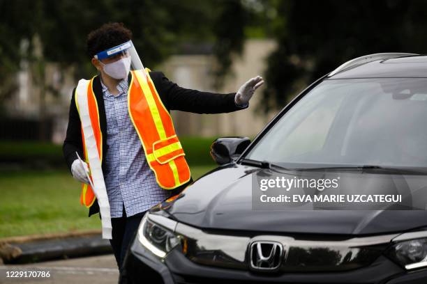 Poll worker waves to voter at a ballot drop box center outside Miami-Dade County Election Department in Miami, Florida on October 19, 2020. Early...