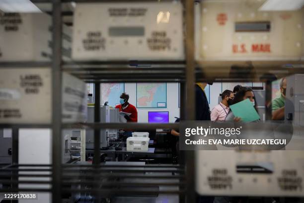An electoral worker scans vote-by-mail ballots at the Miami-Dade County Election Department in Miami, Florida on October 19, 2020. Early voting...