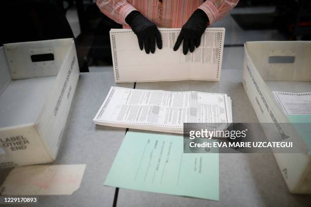 An electoral worker organizes vote-by-mail ballots at the Miami-Dade County Election Department in Miami, Florida on October 19, 2020. Early voting...