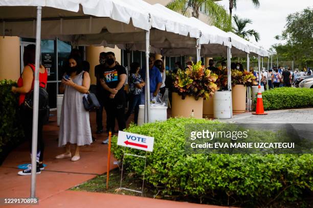 Voters wait in line to cast their early ballots at Miami-Dade County Election Department in Miami, Florida on October 19, 2020. Early voting kicked...