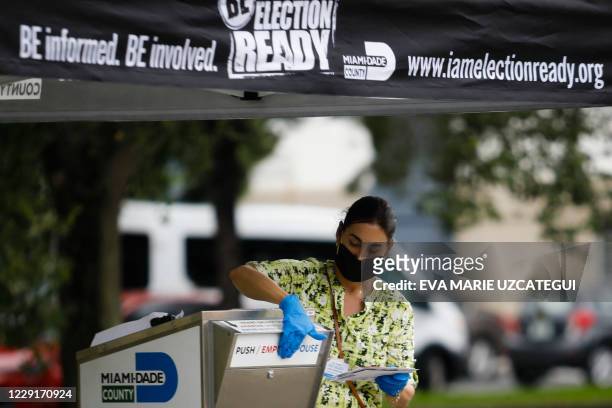Poll worker drops off a vote-by-mail ballot at a ballot drop box at Miami-Dade County Election Department in Miami, Florida on October 19, 2020....