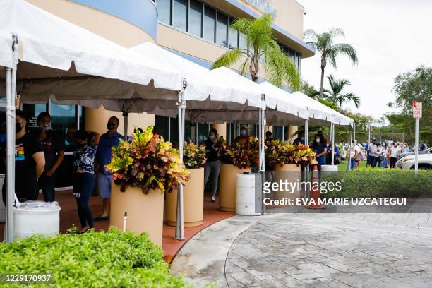 Voters wait in line to cast their early ballots at the Miami-Dade County Election Department in Miami, Florida on October 19, 2020. Early voting...
