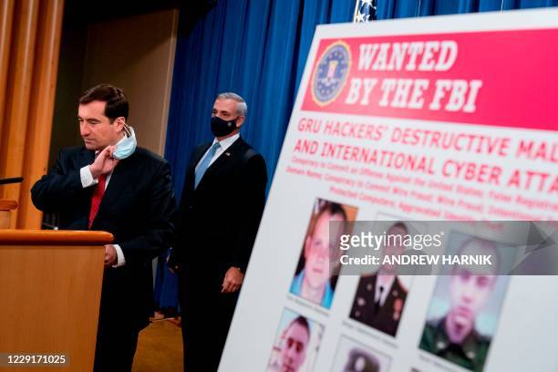 Poster showing six wanted Russian military intelligence officers is displayed as Assistant Attorney General for the National Security Division John...