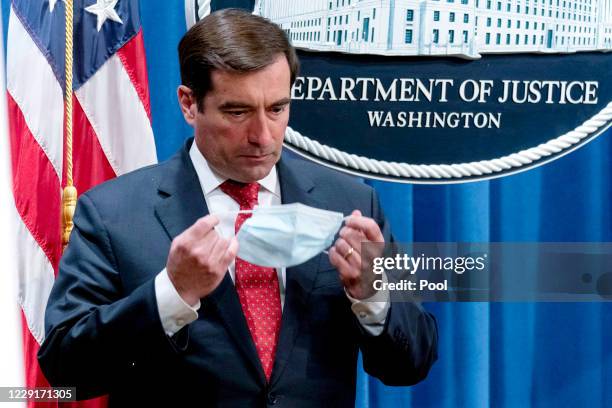 Assistant Attorney General for the National Security Division John Demers puts on a face mask after speaking at a news conference at the Department...