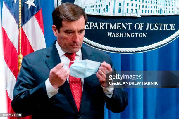 Assistant Attorney General for the National Security Division John Demers puts on a face mask after speaking at a news conference at the Department...