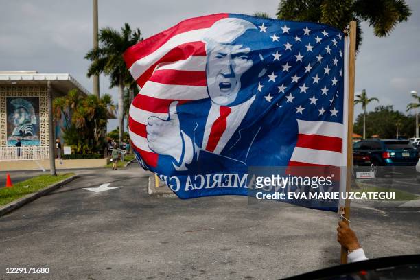 Supporter holds a flag depicting US President Donald Trump's face outside of John F. Kennedy Public Library as voters cast their early ballots in...