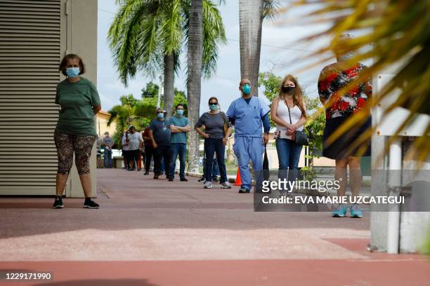 Voters wait in line to cast their early ballots at John F. Kennedy Public Library in Hialeah, Florida on October 19, 2020. Early voting kicked off...