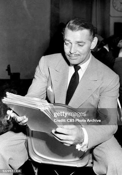 Actor Clark Gable studies his script for a CBS Radio Network performance of "China Seas" December 4 on THE SCREEN GUILD THEATER radio show.