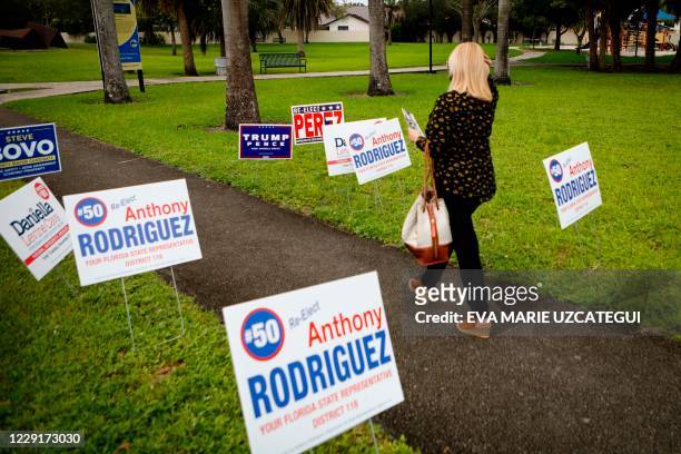 Woman walks past campaign signs at Westchester Regional Library in Miami, Florida on October 19, 2020. - Early voting kicked off Monday in Florida, a...