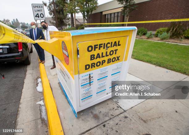 Manuel Lozano, left, Baldwin Park mayor, and Sam Gutierrez, director of public works, view the fire damage to the official ballot drop box where...