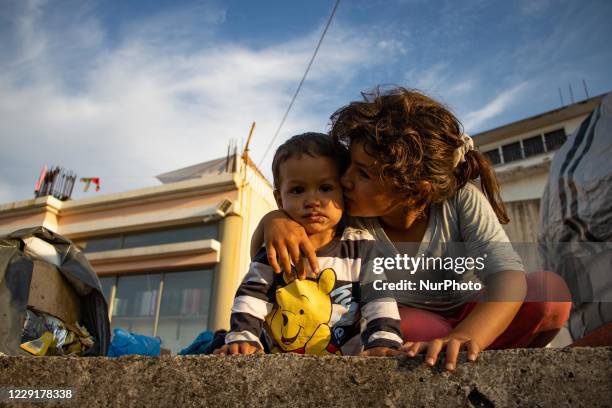 Girl kissing her little brother, siblings living on the terrace of a building in tents after the fire. Portraits of young children refugees, minors...