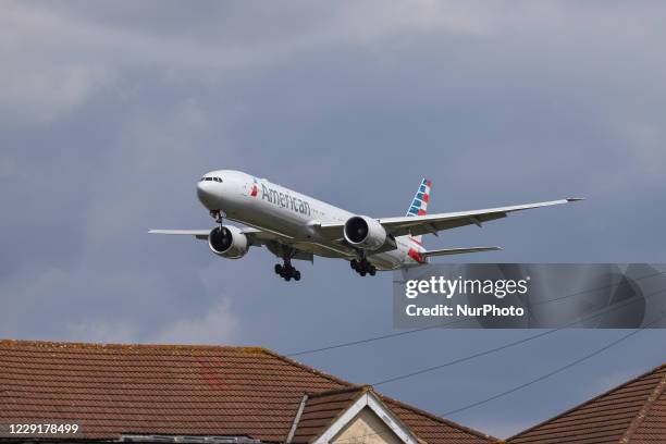 American Airlines Boing 777-300 wide-body aircraft as seen on final approach over the houses of Myrtle Ave, for landing at London Heathrow LHR EGLL...