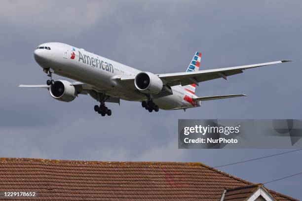 American Airlines Boing 777-300 wide-body aircraft as seen on final approach over the houses of Myrtle Ave, for landing at London Heathrow LHR EGLL...