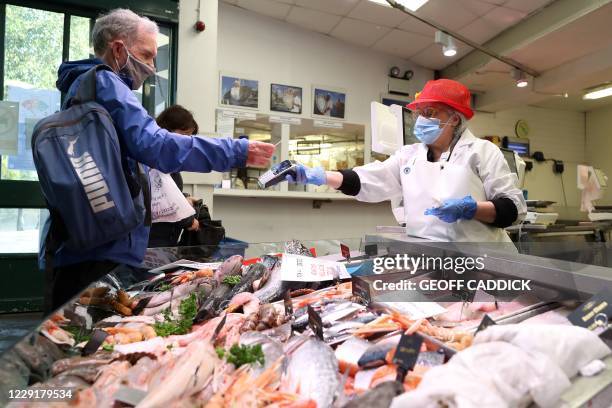 Customer uses a bank card to contactlessly pay for his purchase at a fresh fish stall inside Cardiff Market in Cardiff, south Wales on October 20...