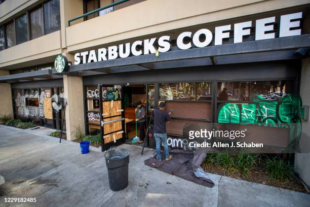 Starbucks Coffee workers clean up broken glass and replace several shattered windows when some Lakers vandals took to the streets and covered several...