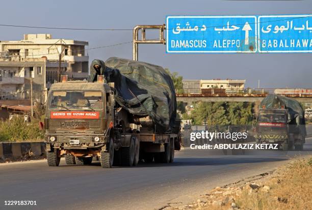 Turkish military vehicles, part of a convoy, drive through the town of Ariha in the rebel-held northwestern Idlib province on October 20 after...