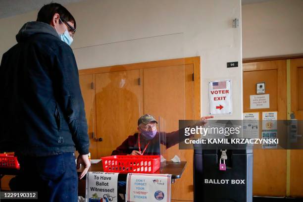 An election worker drops a voter's completed ballot into a ballot box inside City Hall on the first day of in-person early voting for the November...