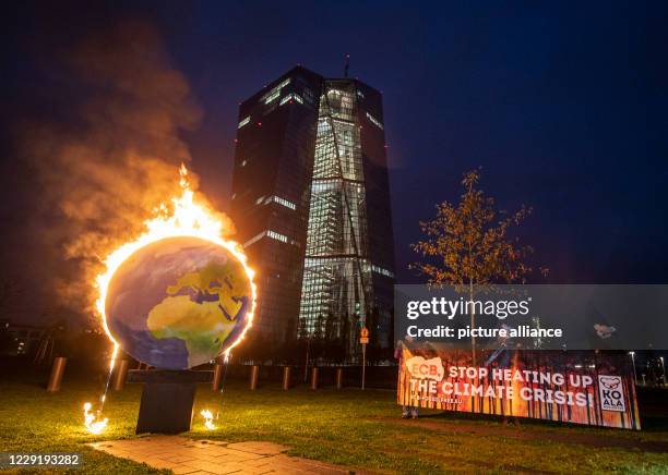 October 2020, Hessen, Frankfurt/Main: With a burning globe, activists of the group "Das Koalakollektiv" demonstrate in front of the European Central...